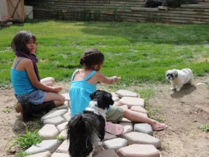 granddaughters lure Flower Shih Tzu with treat.